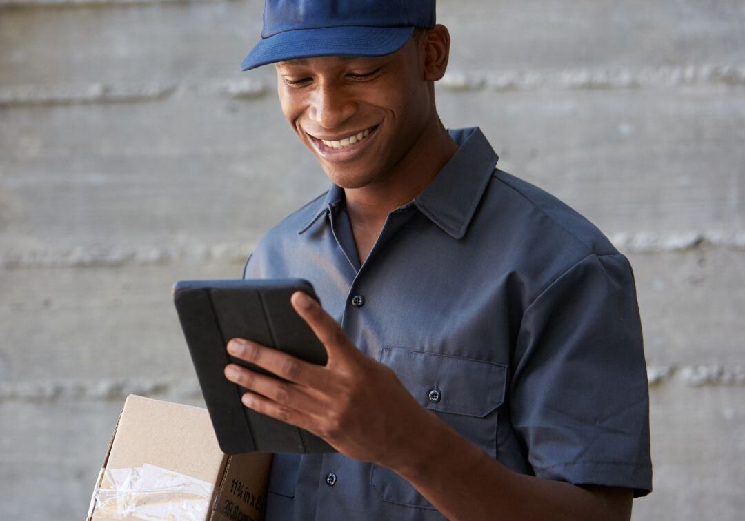 Man looking at a tablet while holding a package.
